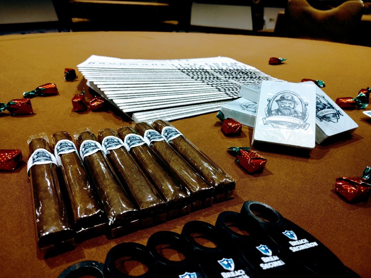 A table of Breach Secure Now giveaways at IT Nation Connect 2021: branded cigars, playing cards, printed handouts and candies